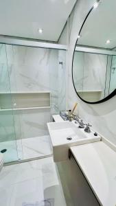 een witte badkamer met een wastafel en een spiegel bij Flat Luxo Jardins com Piscina, Vaga e serviços in Sao Paulo