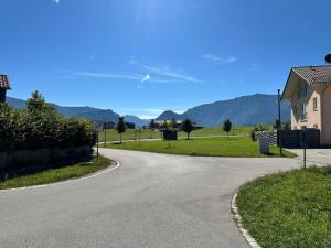 an empty road with a house and mountains in the background at AlpenNest Mountain Oasis in Inzell in Inzell