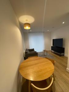 a room with a table and a couch and a screen at Cozy one bed with Large Balcony In Birmingham city center in Birmingham