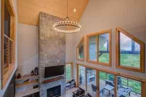 a living room with a stone fireplace and a chandelier at Wine Down at Eagles Nest in Elk Park
