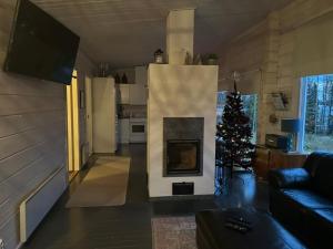 ein Wohnzimmer mit einem Kamin und einem Weihnachtsbaum in der Unterkunft Lapland Lakefront Villa - Northern Lights & Safari in Ranua