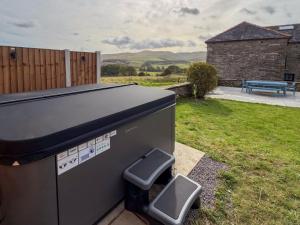un barbecue installé dans une cour avec un banc dans l'établissement Luxury 4-Bed Farmhouse Retreat in Yorkshire Dales, à Gaisgill