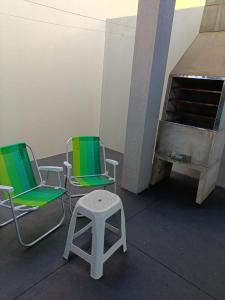 two green and white chairs and a stool in a room at Sobrado de Container Azul in Dourados
