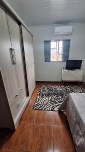 a bedroom with a bed and a desk and a rug at casa kitnet in Maracaju