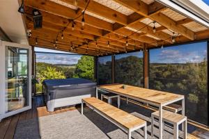 un porche cubierto con mesa y piano en Coastal Serenity - Tapuaetahi Beach Escape, en Purerua