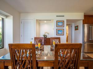 a dining room with a glass table and chairs at Wailea Elua Village 1301 in Wailea