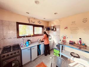 a woman standing in a kitchen preparing food at Cabañas y Hostel I Keu Ken in El Calafate