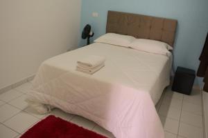 a bedroom with a white bed with two towels on it at Apartamento dalias em Holambra in Holambra