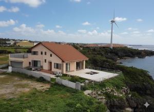 和泊Ocean Villa Okinoerabu的悬崖上的一栋房子，背景是风车