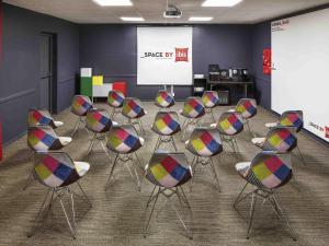 Un grupo de sillas en una sala con una presentación. en Ibis London Luton Airport, en Luton