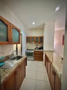 a large kitchen with a sink and a stove at Depa 102A en Huatulco con alberca y terraza 5 min playa in Santa Cruz Huatulco