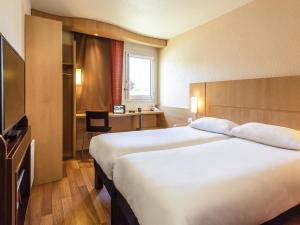 a hotel room with a large bed and a desk at Ibis Château-Thierry in Essômes-sur-Marne