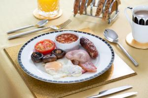 um prato de alimentos com ovos, salsichas e tomates em B&B Meadow View em Penrith