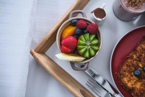 a table with a bowl of fruit and a plate of food at Étoile du Lac Lyster - Spa & Vue sur le Lac in Coaticook