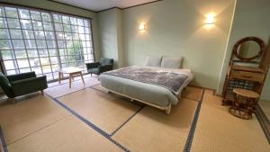 a bedroom with a bed and two chairs and a window at Nona Madarao in Madarao Kogen