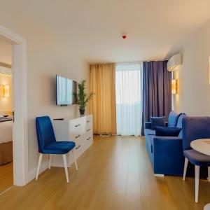 a hotel room with two blue chairs and a tv at Panorama Luxury SeaView in Batumi