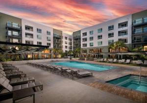 a swimming pool with chairs and a building at Luxe Deco Haven with Pool, Gym & Parking Close to Disneyland in Tustin