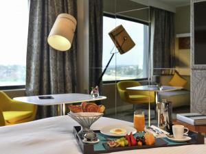 Una habitación de hotel con una bandeja de comida en una cama. en Pullman Abidjan, en Abiyán
