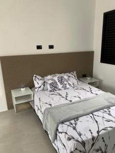 a bedroom with a large bed and two tables at Loft de luxo em Peruíbe, 3 minutos da praia in Peruíbe