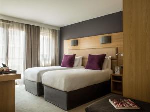 a hotel room with two beds with purple pillows at Grand Hôtel Roi René Aix - MGallery Collection in Aix-en-Provence