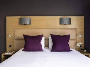 a bedroom with a bed with purple pillows at Grand Hôtel Roi René Aix - MGallery Collection in Aix-en-Provence