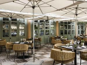 a restaurant with tables and chairs and umbrellas at Grand Hôtel Roi René Aix - MGallery Collection in Aix-en-Provence