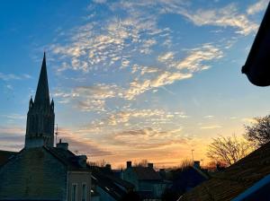 a church steeple with a cloudy sky above a city at La suite Nacrée - Magnifique Studio in Bernières-sur-Mer