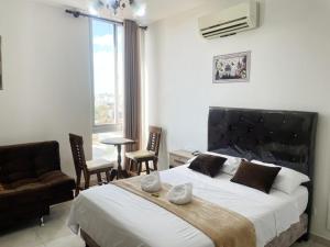 ein Schlafzimmer mit einem großen Bett und Stühlen sowie einem Fenster in der Unterkunft Confort & Céntrico Full Equipado Turístico in Santa Cruz de la Sierra