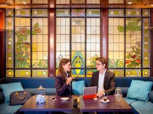 two people sitting in a restaurant with a laptop at Mercure Lyon Centre Château Perrache in Lyon