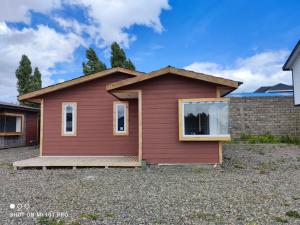 a red house with windows on a gravel driveway at Cabañas 1 Olimai in Puerto Natales