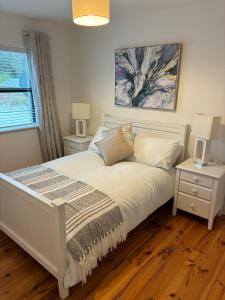 キンバーラにあるKinvara harbour retreatの白いベッドと2つのナイトスタンドを備えた寝室