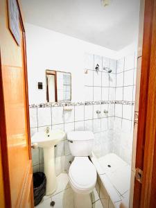 a white bathroom with a toilet and a sink at Hospedaje Carrasco Cajamarca in Cajamarca +39 photos