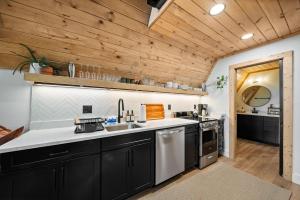 a kitchen with black cabinets and a wooden ceiling at Ascent A-Frame at Calm Ridge Treehouses in Boone +15 photos
