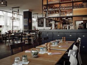 ケルンにあるHotel Mondial am Dom Cologne MGalleryの木製のテーブルと椅子、バーのあるレストラン