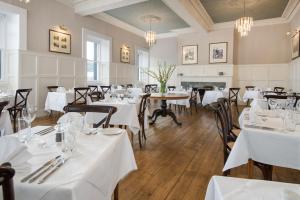 a restaurant with white tables and chairs and a fireplace at The Inveraray Inn, BW Signature Collection in Inveraray