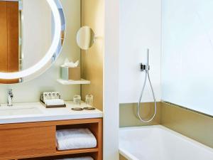 a bathroom with a sink and a tub and a mirror at Sofitel Luxembourg Europe in Luxembourg