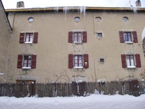 a building with red shuttered windows and a fence at La Maison Bleue in La Cabanasse