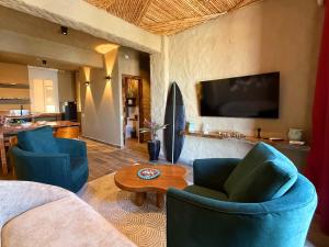 a living room with two blue chairs and a tv at Hotel Quincha y Adobe in Huanchaco