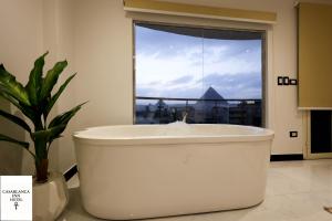 a white bath tub in a bathroom with a window at Casablanca pyramids inn in Cairo +49 photos
