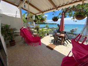 a patio with red chairs and a table and the ocean at Hostal Hilltop Sapzurro in Zapzurro