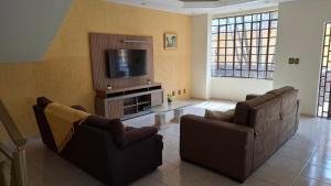 a living room with two couches and a tv at Casa Jardim da Serra in Juiz de Fora