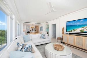 a living room with white furniture and a large screen tv at Beachcomber 35 in George Town +27 photos