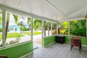 a room with green walls and windows and a table and chair at Private Cottage on Bayfront Estate with Pool, Beach, Dockage, Kayaks and More in Islamorada