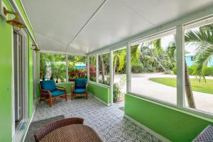 a porch with two blue chairs and windows at Private Cottage on Bayfront Estate with Pool, Beach, Dockage, Kayaks and More in Islamorada