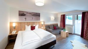 a bedroom with a large white bed and a couch at Hotel Bergland Superior in Sankt Leonhard im Pitztal