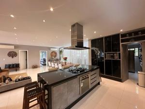 a large kitchen with a stove top oven next to a living room at Casa Alto Padrão - Riviera de São Lourenço in Bertioga