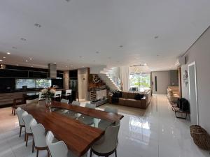 a kitchen and living room with a wooden table and chairs at Casa Alto Padrão - Riviera de São Lourenço in Bertioga