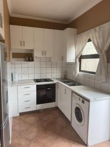 Una cocina con gabinetes blancos y lavavajillas. en Cozy Place in Windhoek, en Windhoek