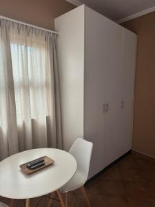 Una mesa y sillas blancas y un armario blanco. en Cozy Place in Windhoek, en Windhoek 1 foto más