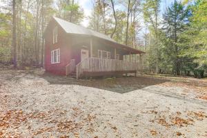 una casa roja con terraza en el bosque en 8 Private Acres Little Mahoning Creek Cabin!, en Northern Cambria